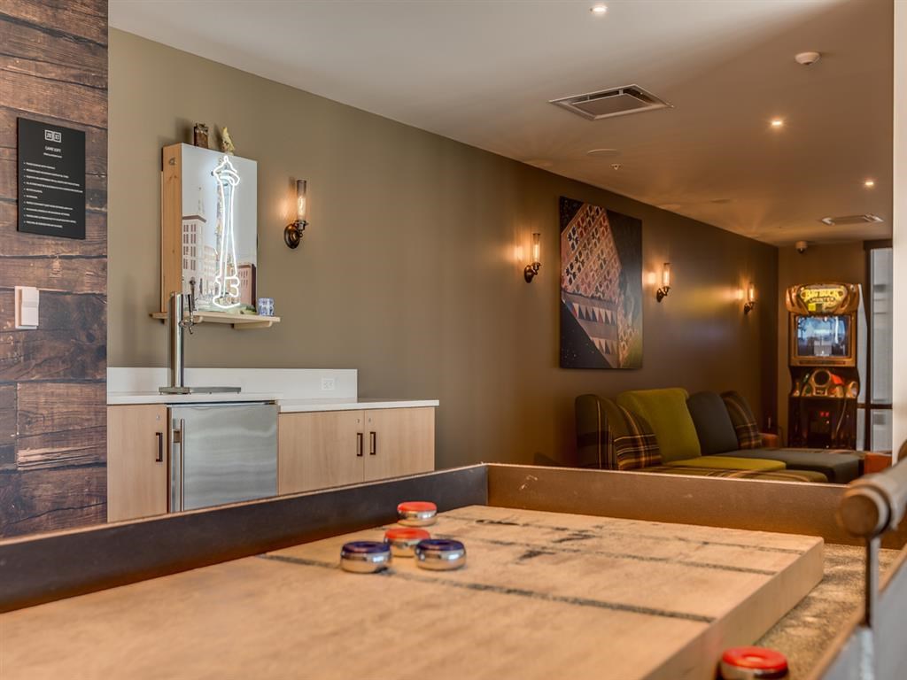 a long wooden table in a room with a kitchen and a couch