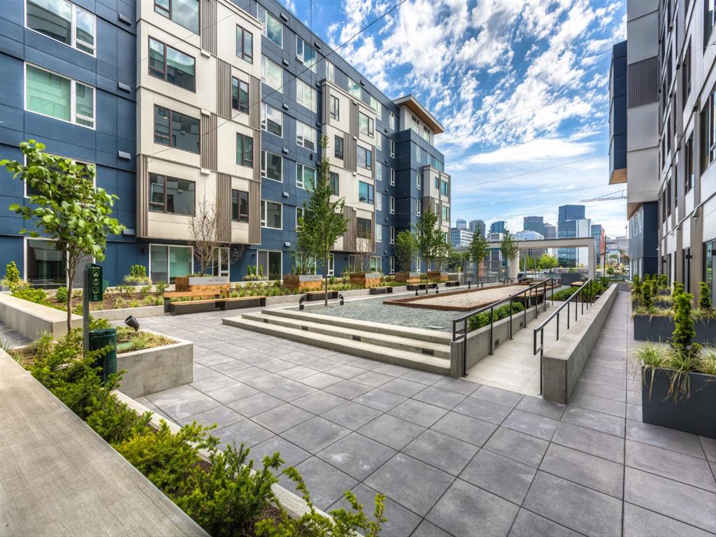 an outdoor area with benches and trees in front of an apartment building
