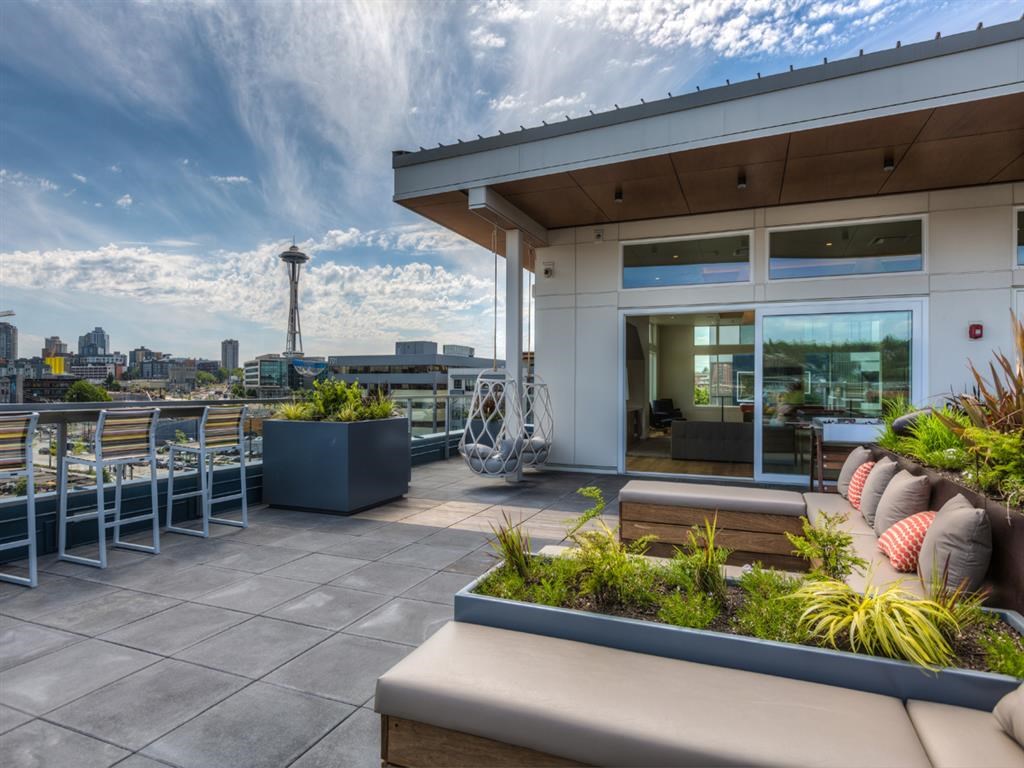 a rooftop patio with furniture and a city in the background