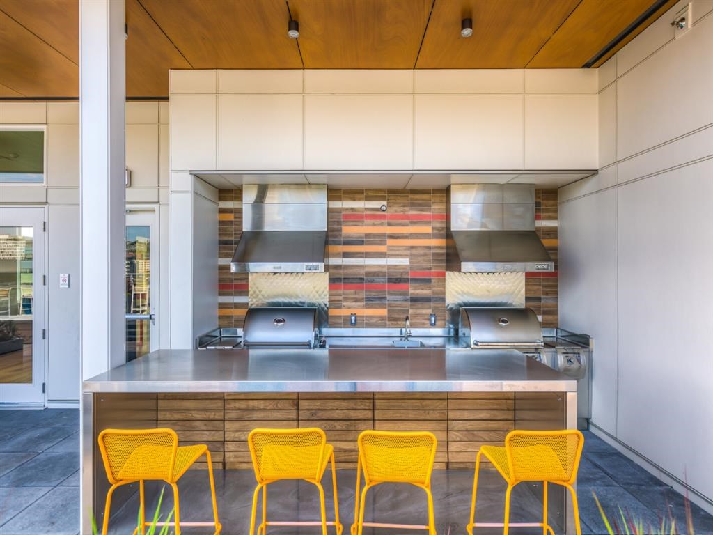 a kitchen with yellow chairs and stainless steel counter tops