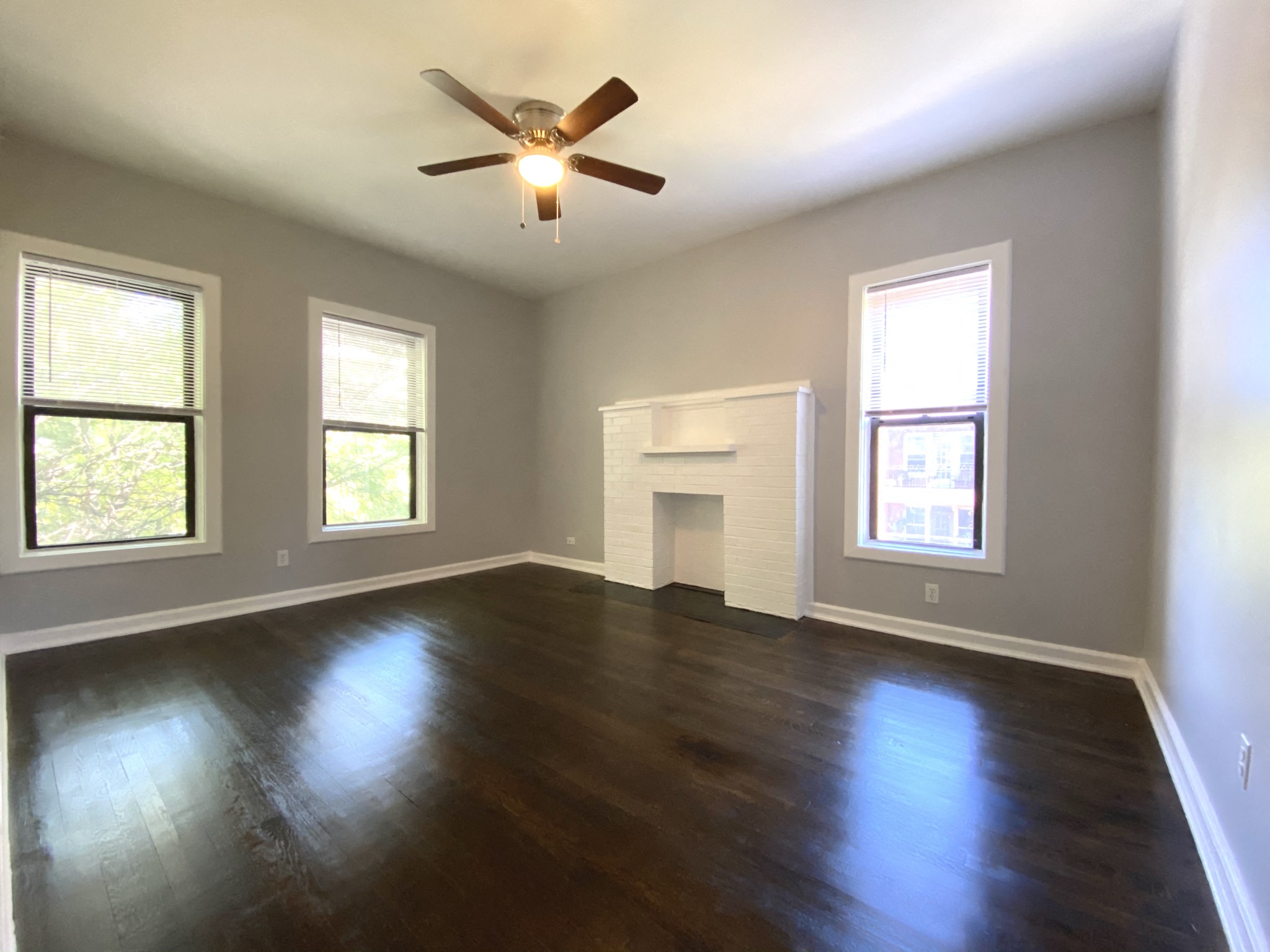 an empty living room with a ceiling fan and a fireplace