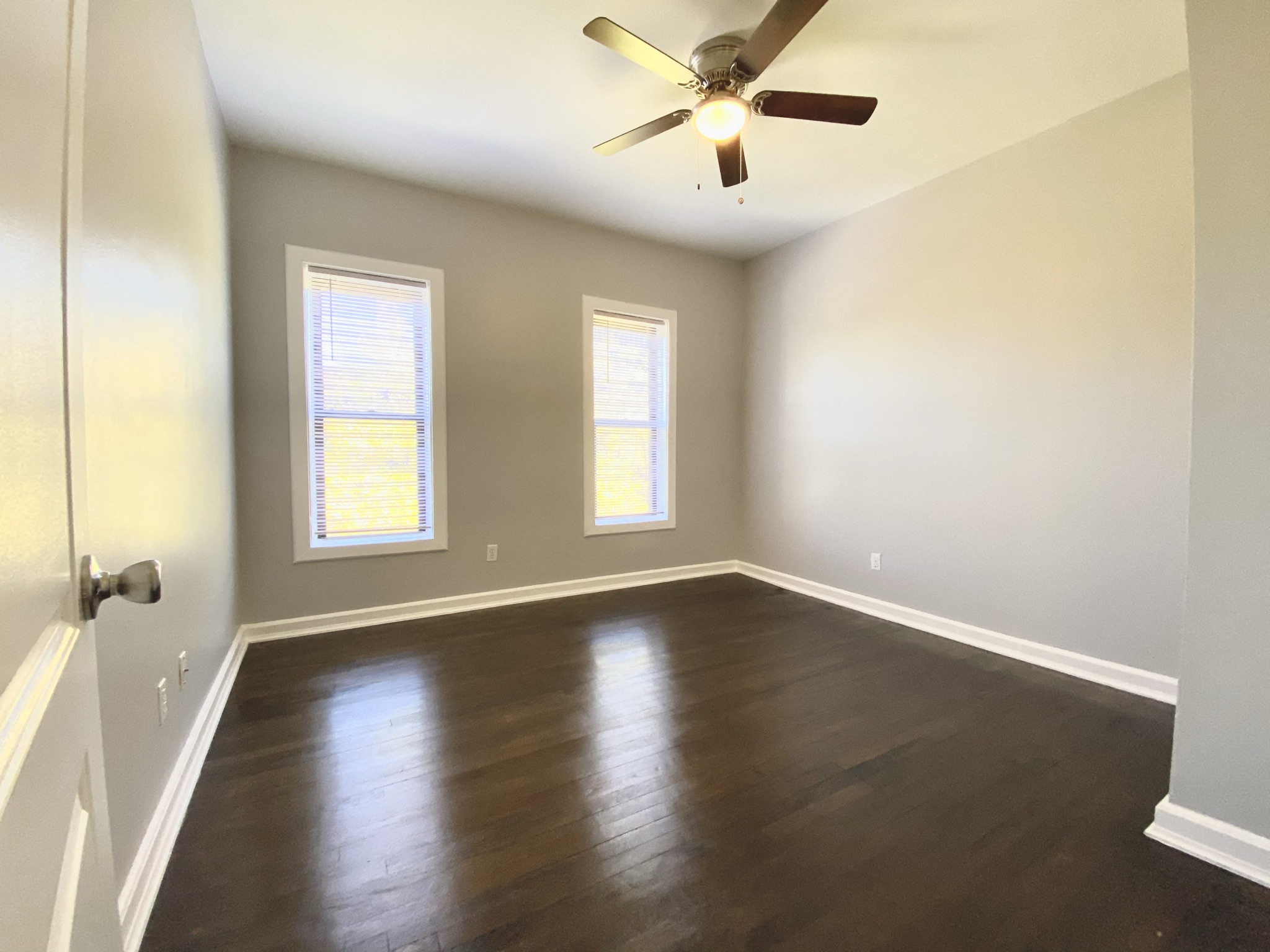an empty living room with wood floors and a ceiling fan