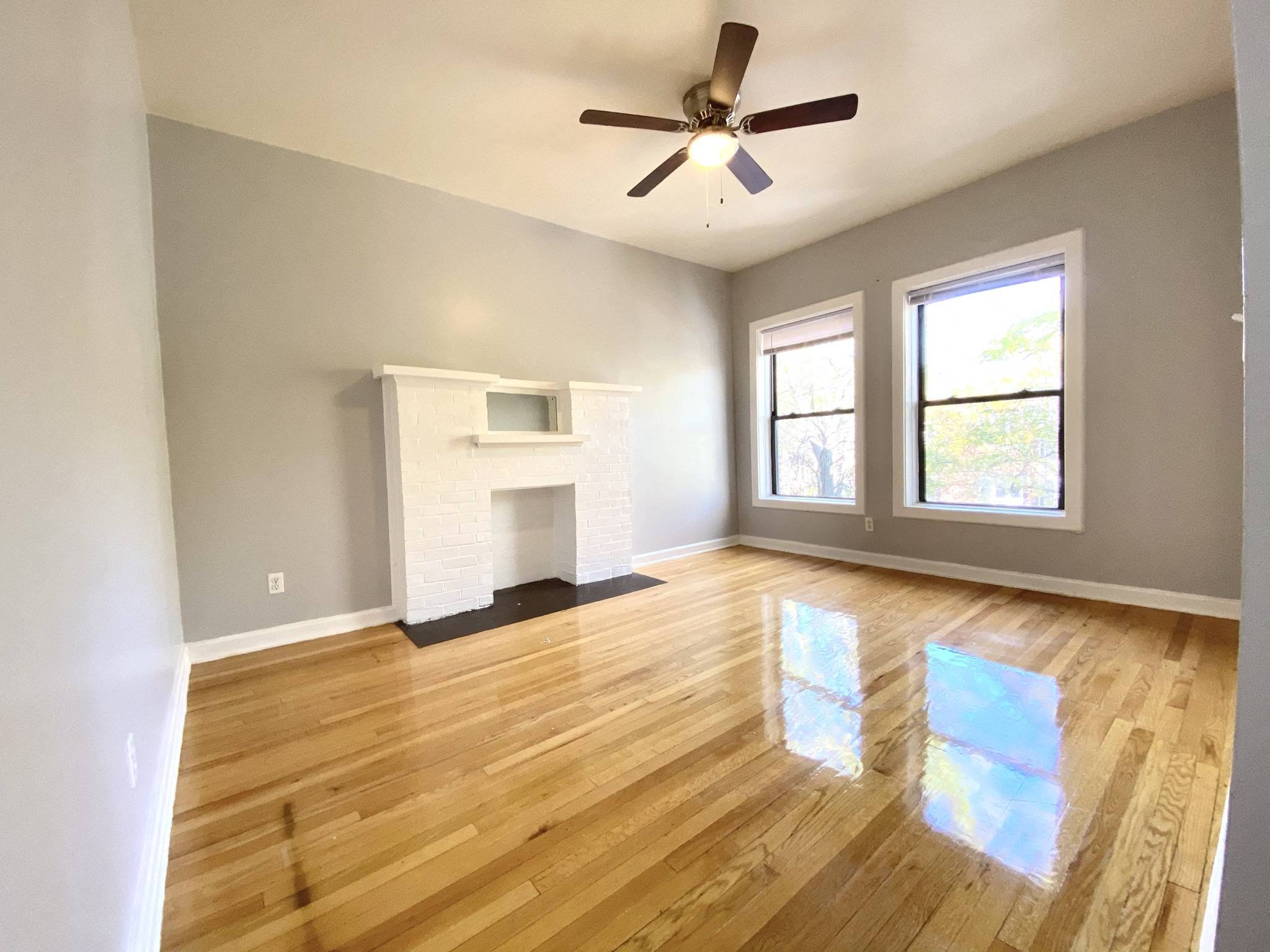 an empty living room with a fireplace and a ceiling fan