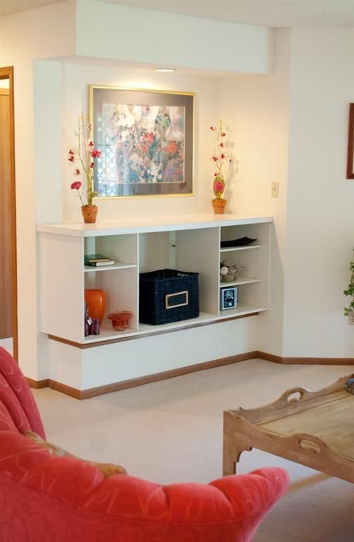 a living room with a shelf and a picture