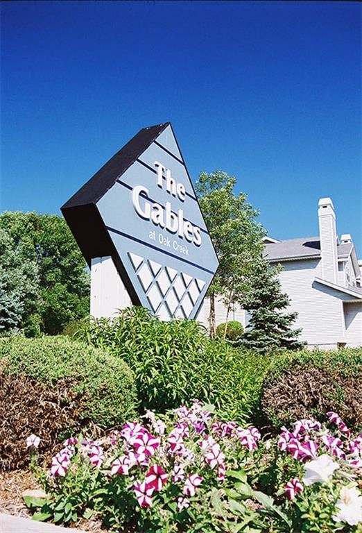 a sign for the gables at olde towne with flowers
