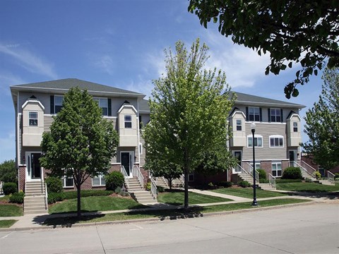 an apartment building with stairs and trees in front of it