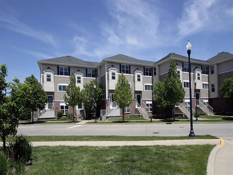 an apartment building with stairs and trees in front of it