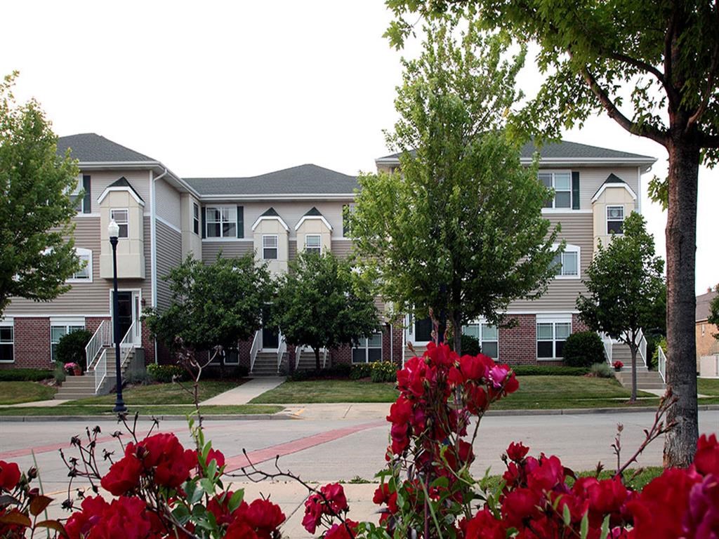 an apartment building with red flowers in front of it