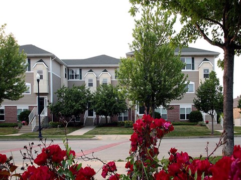 an apartment building with red flowers in front of it