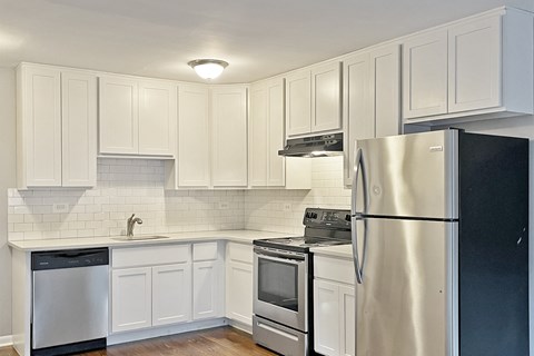 A kitchen with white cabinets and a black refrigerator.