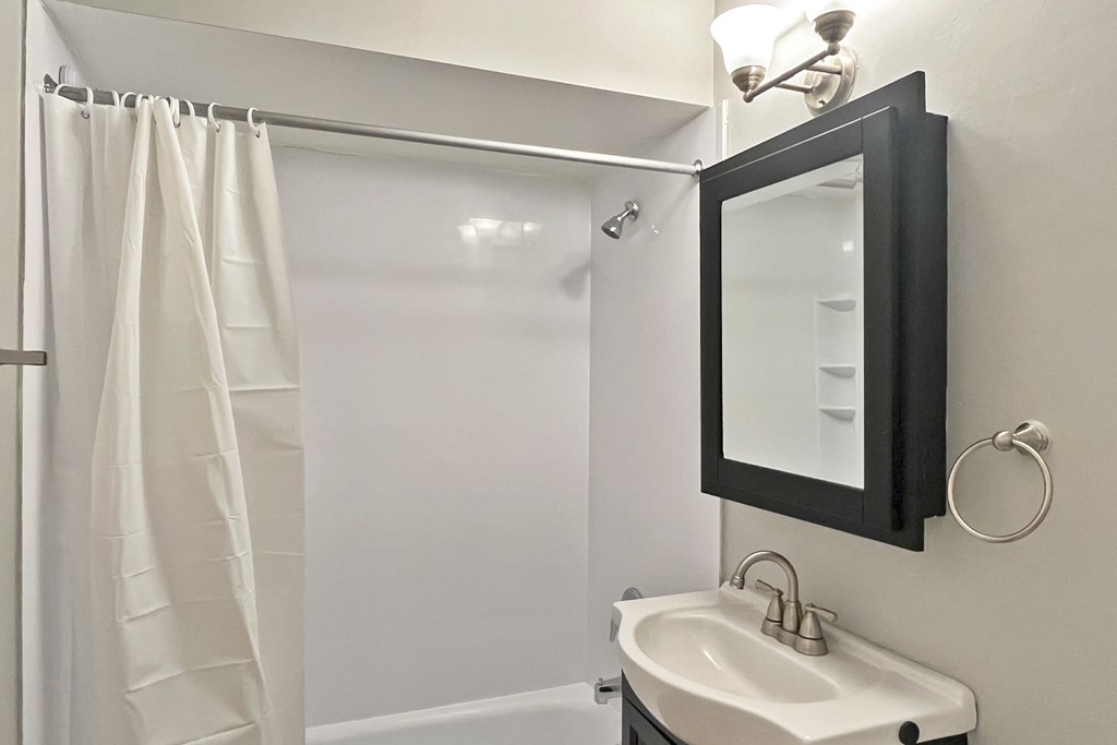 A white sink in a bathroom with a mirror above it.