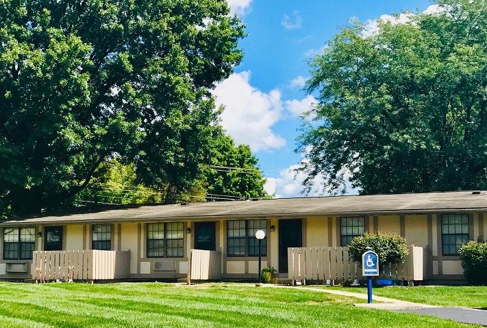an apartment building with a lawn and trees