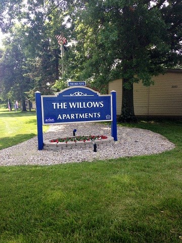 a sign for the willows apartments in front of a lawn