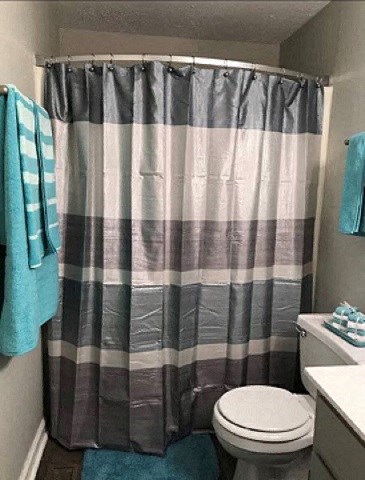 a bathroom with a striped shower curtain and a toilet