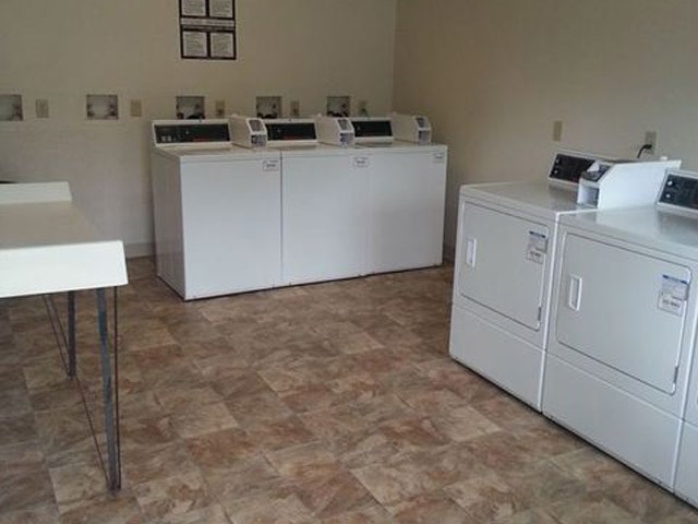 three washes and dryers in a room with a table