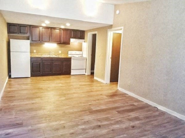 an empty living room and kitchen with wood floors