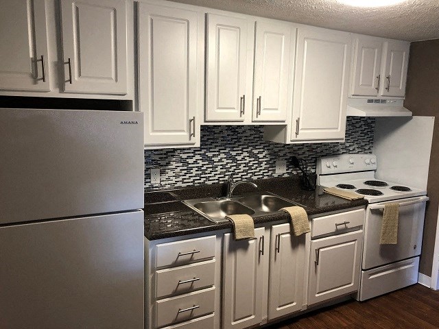 a kitchen with white cabinets and a sink and a refrigerator