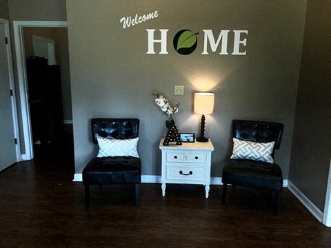 a living room with two chairs and a home sign