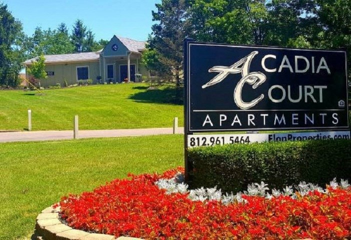 a cada court apartments sign in front of a yard with red flowers