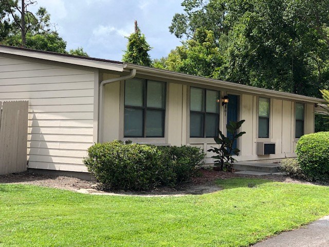 a small white house with a lawn and bushes