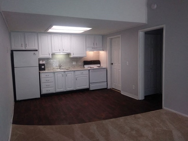 an empty kitchen with white cabinets and a refrigerator