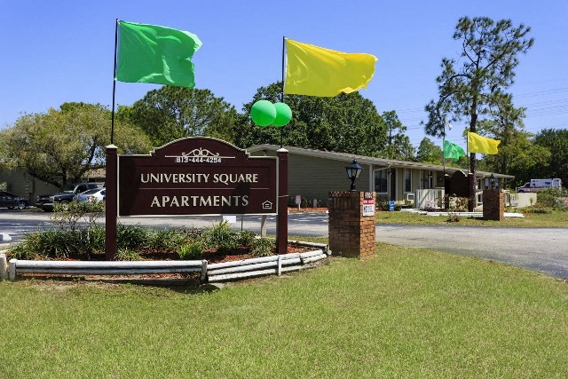 a sign for the university square apartments in front of a building