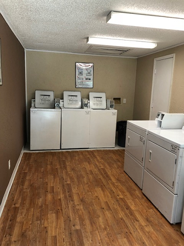 four washers and dryers in a room with a wood floor