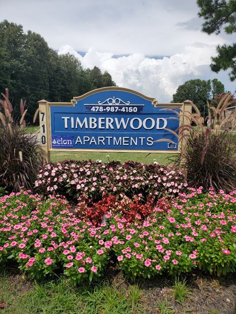 a sign for timbrewood subdivision with pink and white flowers