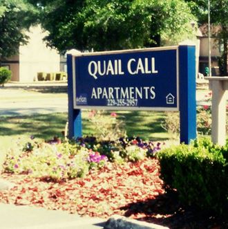 a sign forqual call apartments in front of a sidewalk
