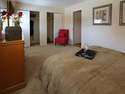 A bedroom with a bed, chair, and a wooden dresser.