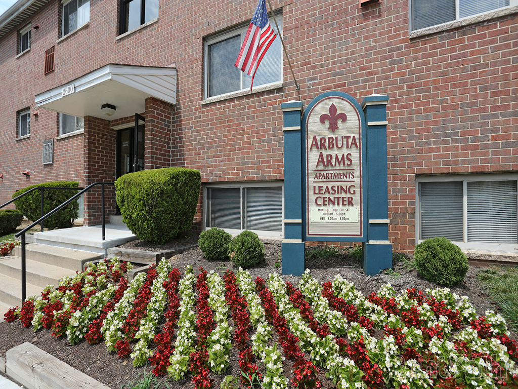 A brick building with a sign that says Arbutus Arms Apartments Leasing Center.