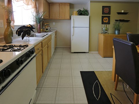 A kitchen with a white refrigerator and a black chair.
