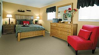 A bedroom with a bed, dresser, and chair.