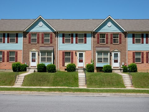 A blue and red brick house with a white door and windows.