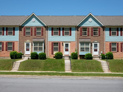 A blue and red brick house with a white door and windows.