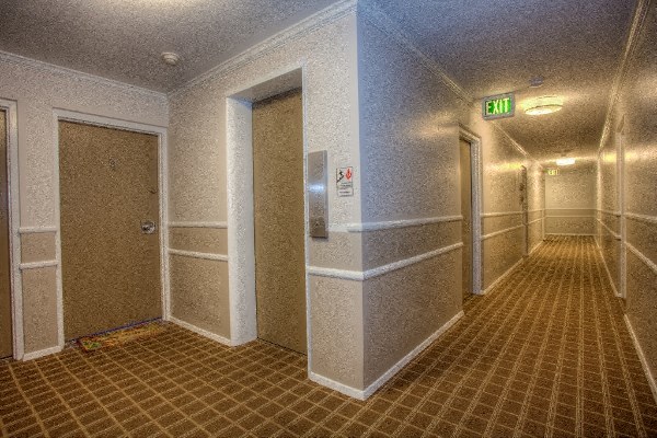 the hallway of a hotel lobby with doors and a exit sign