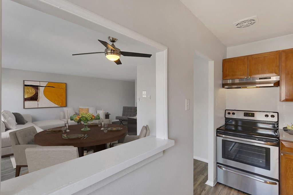 a kitchen and living room with stainless steel appliances and a ceiling fan