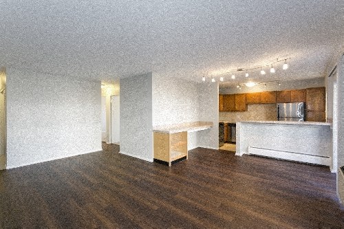an empty living room and kitchen with a wood floor