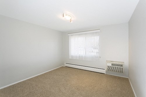 an empty living room with a window and a radiator