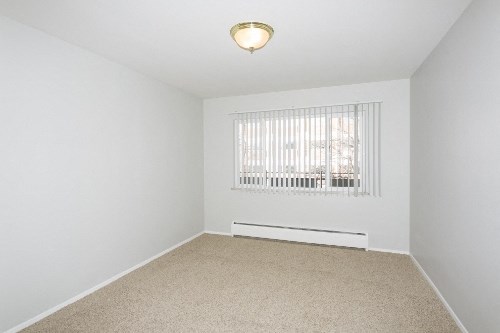 an empty room with a window and a carpeted floor