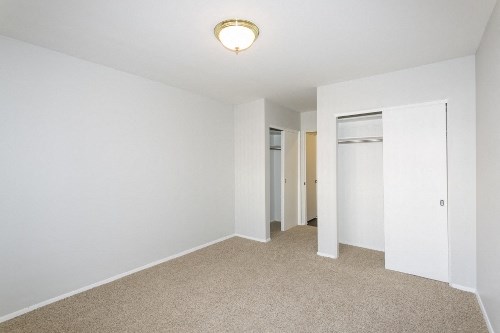 an empty living room with white walls and a door to a closet