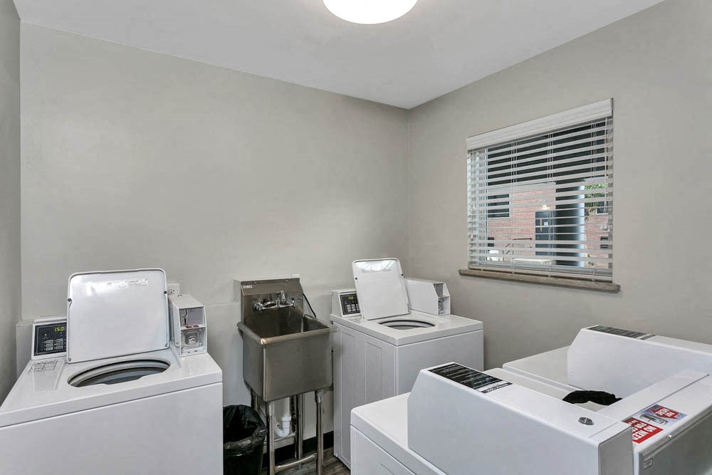 a laundry room with four washing machines and a window