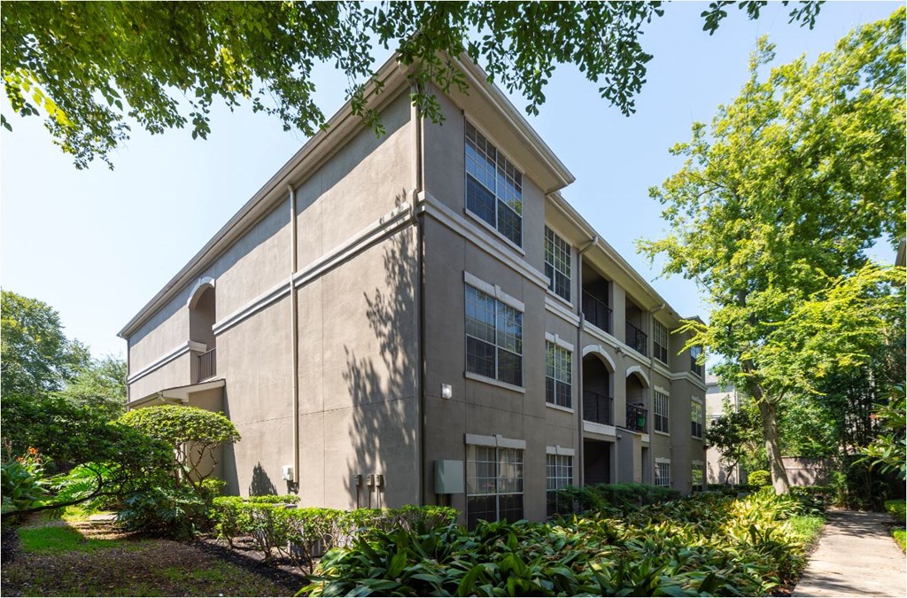 a large building with trees and bushes in front of it