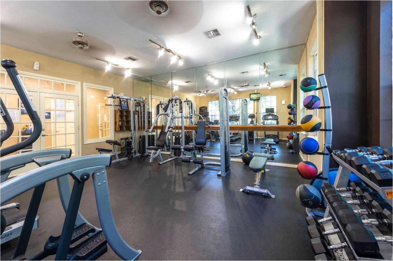 a gym with weights and cardio equipment on the floor and mirrors