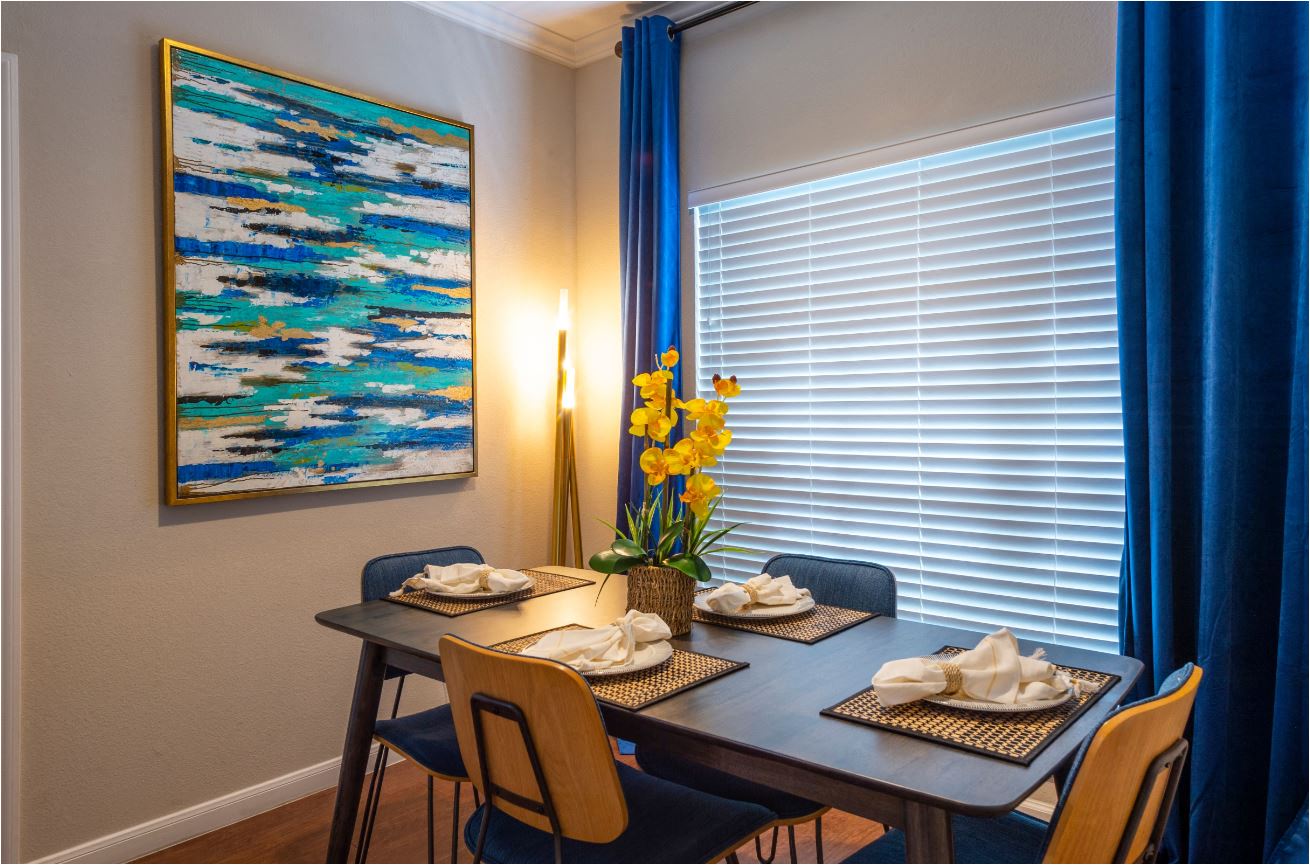 a dining room with a table and chairs and a painting on the wall