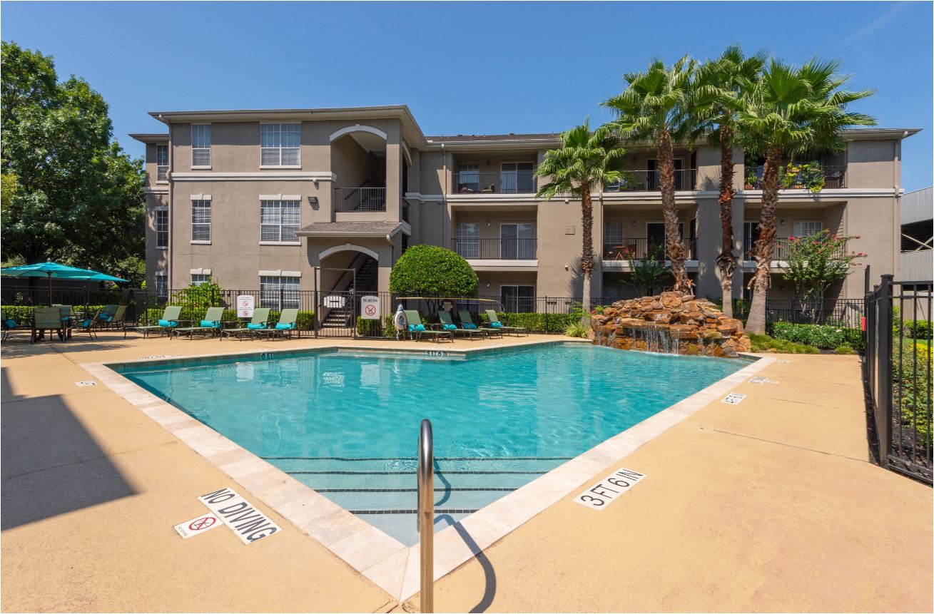 a swimming pool in front of a building with palm trees