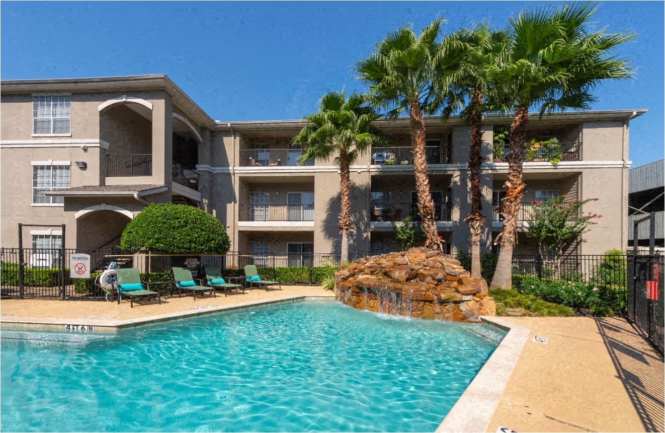 a swimming pool with palm trees in front of an apartment building