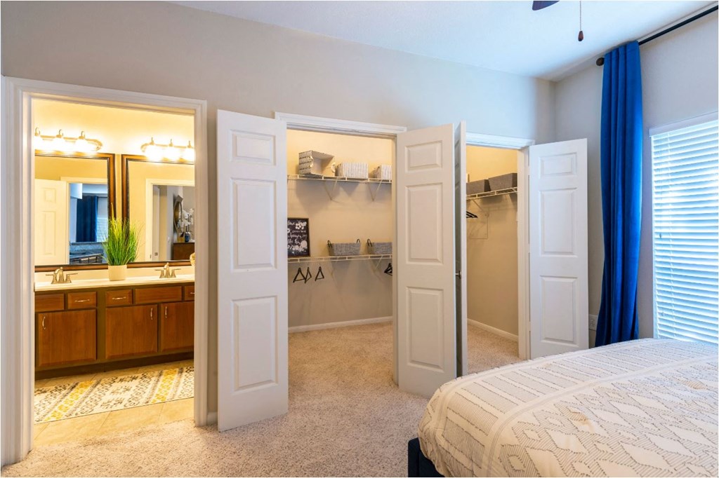 a bedroom with a closet and a bathroom with a sink