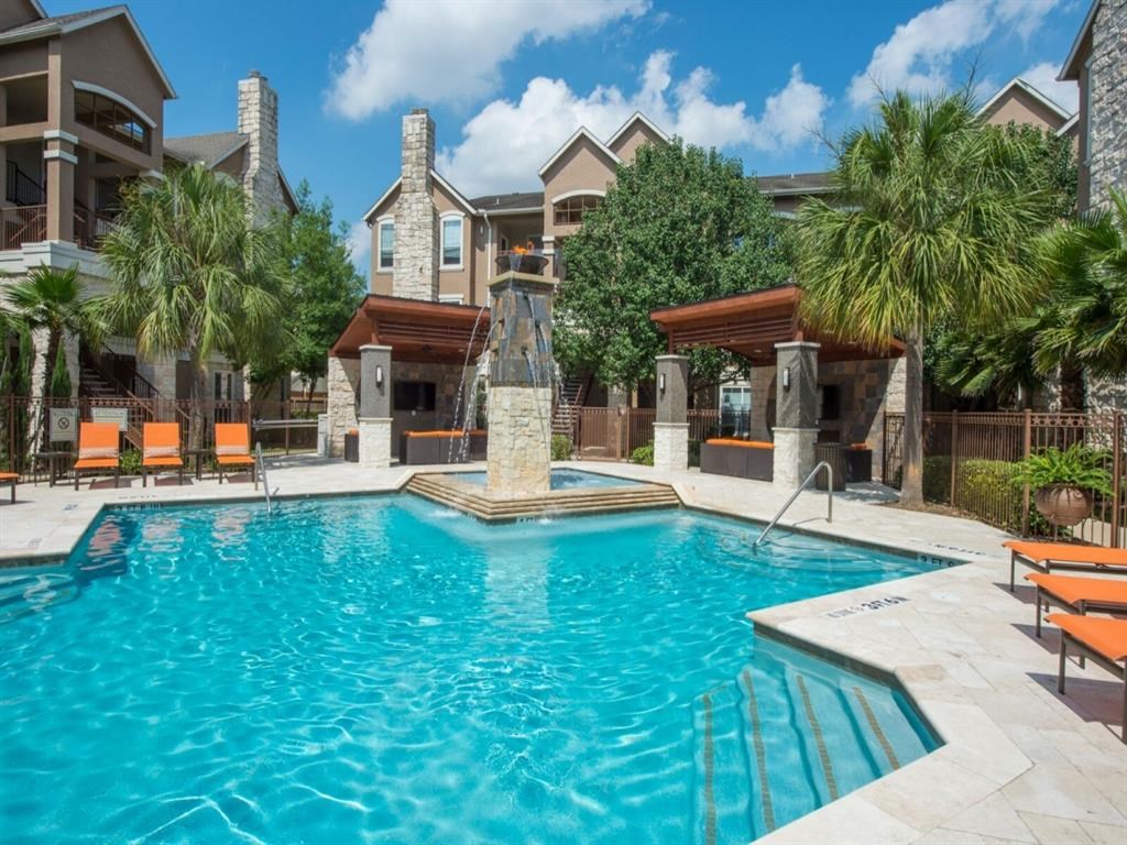 a swimming pool with palm trees and a building in the background