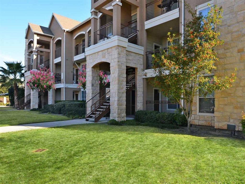 an apartment building with a green lawn and stairs